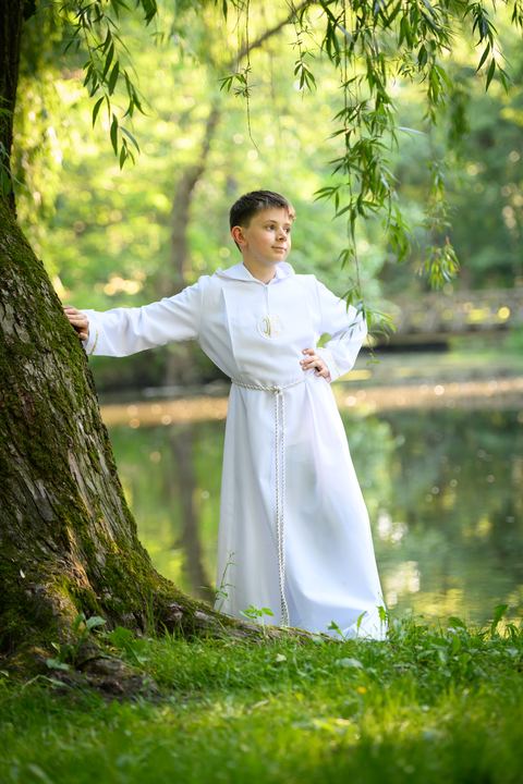 Chłopiec w albie nad brzegiem stawu
